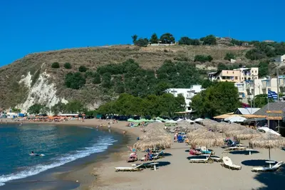 a beach with straw umbrellas and people on the beach at Villa Katerina Pente by Villa Plus in Kalyves