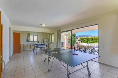 a living room with a ping pong table and a patio at Villa Margarita Exi by Villa Plus in Kalyves