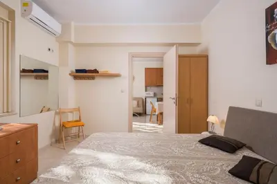 a bedroom with a large bed and a kitchen at Luxury Coastal Retreat, Mountain View Balcony with Palm Trees & Parking in Chania Town