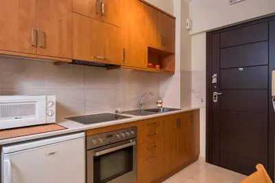 a kitchen with wooden cabinets and a sink and a microwave at Luxury Coastal Retreat, Mountain View Balcony with Palm Trees & Parking in Chania Town