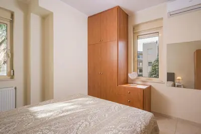 a bedroom with a bed and a wooden cabinet at Luxury Coastal Retreat, Mountain View Balcony with Palm Trees & Parking in Chania Town