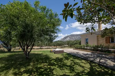 a yard with a tree and a building with a mountain at Villa Ciel in Agios Padeleimon