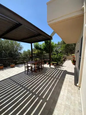 a patio with a table and chairs under a roof at Koundouros Home in AmigdhalokeFálion