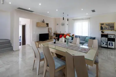 a dining room and living room with a table and chairs at Villa Denise in Kalyves