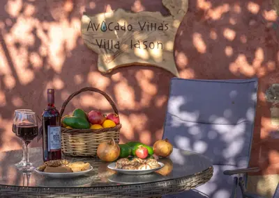 a table with a basket of fruit and a bottle of wine at Avocado Villas in Chania Town