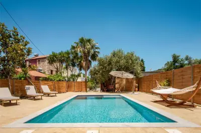 a swimming pool with a hammock and a fence at Avocado Villas in Chania Town