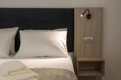 a bedroom with a bed with white sheets and a lamp at Quarters Luxury Apts in Chania Town