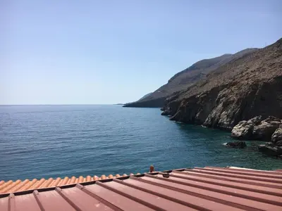 a view of a body of water next to a cliff at Great sea-view apartment. in Khóra Sfakíon