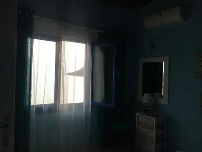 a room with two windows with curtains and a television at Great sea-view apartment. in Khóra Sfakíon