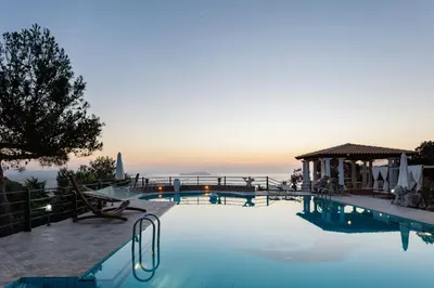 a swimming pool with a sunset in the background at Villa Paparouna in Chania Town