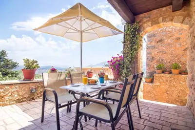 a table and chairs with an umbrella on a patio at Samonas - Blue villa Mantzourana in Khiliomoudhoú