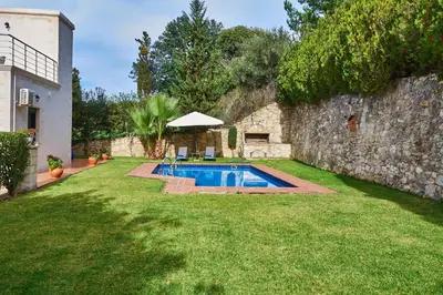 a swimming pool in a yard next to a stone wall at Villa Elia by PosarelliVillas in Vryses