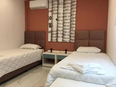 a bedroom with two beds and a wall with a window at Πολυτελές οροφοδιαμέρισμα για ονειρικές διακοπές! in Chania Town