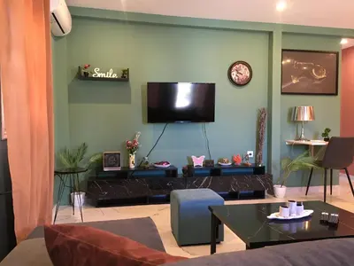 a living room with a couch and a tv on the wall at Πολυτελές οροφοδιαμέρισμα για ονειρικές διακοπές! in Chania Town