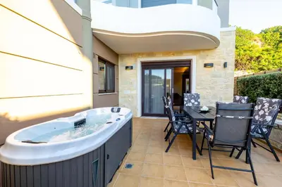 a hot tub on a patio with a table and chairs at Villy Luxury Home by the Sea 1 in Ayiá