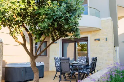 a table and chairs under a tree next to a building at Villy Luxury Home by the Sea 1 in Ayiá