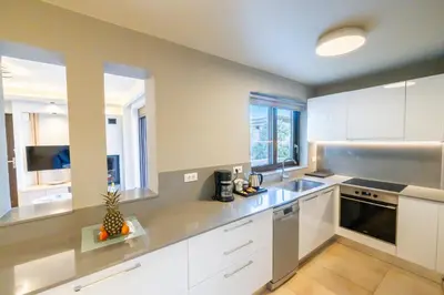 a kitchen with white cabinets and a sink at Villy Luxury Home by the Sea 1 in Ayiá
