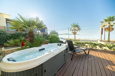 a hot tub on a deck with a table and a chair at Villy Luxury Home by the Sea 2 in Ayiá