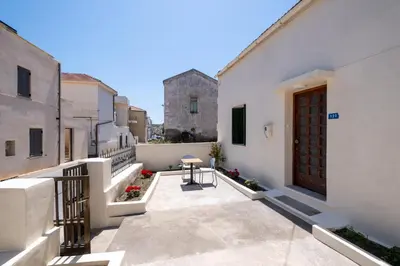 a balcony with white buildings and a wooden door at Jasmine Home by the Sea by 8essentially in Kalyves
