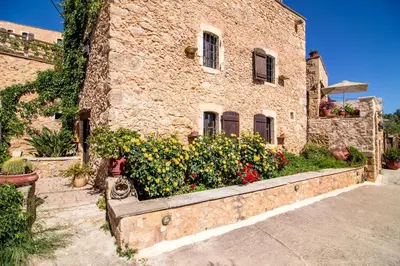 a stone building with flowers in front of it at Samonas - Orange villa Diktamos in Khiliomoudhoú
