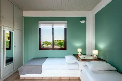 a blue bedroom with two beds and a window at ApteraMare Tradidtional house 'New listing' in Chania Town