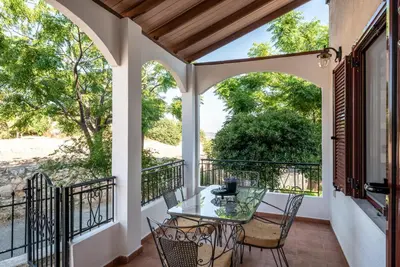 a patio with a glass table and chairs on a balcony at ApteraMare Tradidtional house 'New listing' in Chania Town