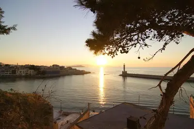 a sunset over a body of water with a lighthouse at Auntie's home by Chania Old Harbor in Chania Town