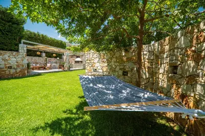 a hammock in a yard next to a stone wall at Casa dei Sogni in Nerokoúros