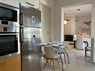 a kitchen with a table and a stainless steel refrigerator at Central apartment in quiet neighborhood near sandy beach in Chania Town