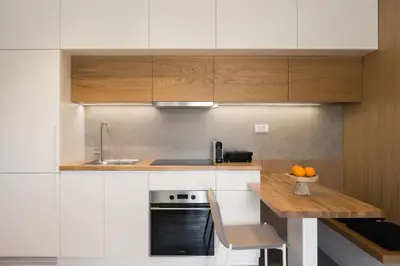 a kitchen with white cabinets and a table with oranges on it at Noemie Luxury Suites in Chania Town