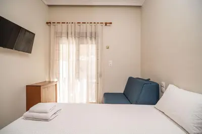 a bedroom with a bed and a blue chair at Casa Armonia Seaside by 8essentially in Chania Town
