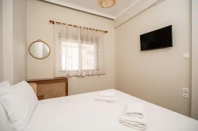 a white bedroom with a bed and a tv at Casa Armonia Seaside by 8essentially in Chania Town
