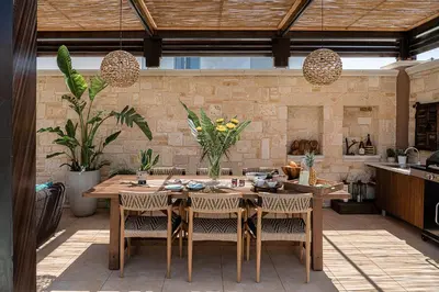 an outdoor kitchen with a wooden table and chairs at Villa Peacock with Spa Facilities in Daratso