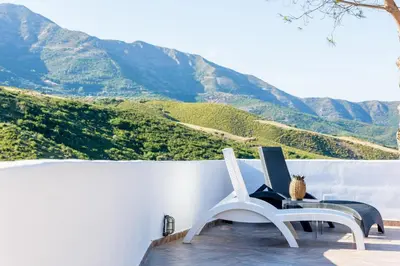 a laptop on a chair on a balcony with mountains at Ktima Abella ✩ Organic Garden ✩ Absolute Privacy in Élos