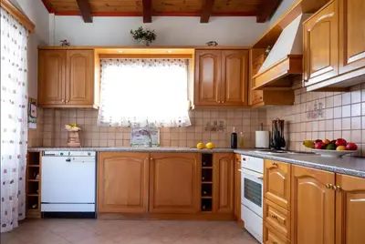 a kitchen with wooden cabinets and a white dishwasher at Ktima Abella ✩ Organic Garden ✩ Absolute Privacy in Élos