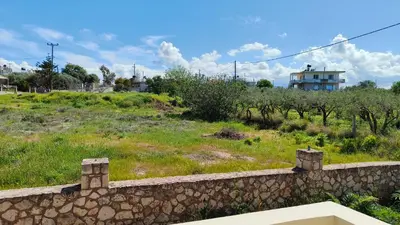a stone wall in front of a field with a building at Pazinos/Neveli Cottage in Galangádhos