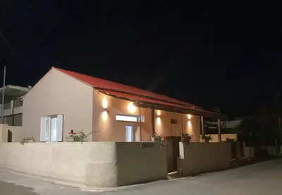 a white house with a red roof at night at Landro House in Kissamos