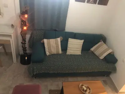 a living room with a green couch with pillows at Summer mood in Chania Town