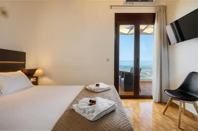 a bedroom with a bed and a chair and a television at Villa Nektar with private ecologic pool and amazing view! in Kondópoula