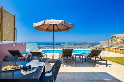 a patio with tables and an umbrella and a pool at Villa Nektar with private ecologic pool and amazing view! in Kondópoula