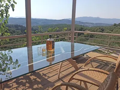 a glass table on a balcony with two chairs at Eco Friendly Country Home in Kókkinos Pírgos