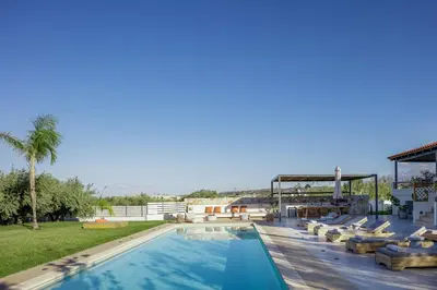 a large swimming pool with lounge chairs on a resort at Quiet Villa Aviana,garden, heated pool,BBQ,jacuzzi in Gerani Chanion