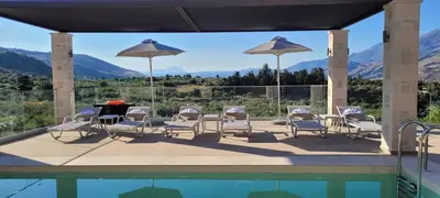 a patio with a table and chairs and a pool at Splendid Villas and Family Resort in Kalamitsi Amygdali