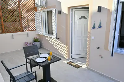 a small patio with a table and chairs and a door at Artemis No.2 Apartment in Kissamos