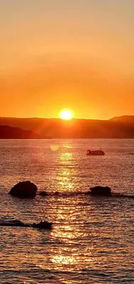 a sunset over a body of water with rocks at Rika’s Luxury seaside apartment in Chania Town