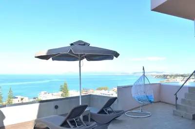 a balcony with two chairs and an umbrella at Galini Sea View Hotel in Agia Marina Nea Kydonias