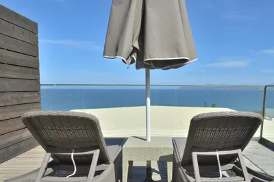 two chairs and an umbrella on a deck with the ocean at Galini Sea View Hotel in Agia Marina Nea Kydonias