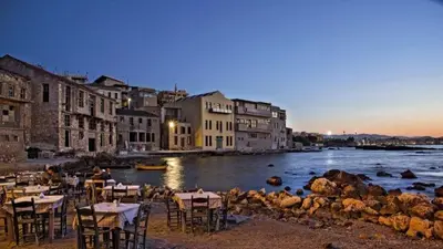 a group of tables and chairs next to a body of water at Studio Victory Chania in Chania Town