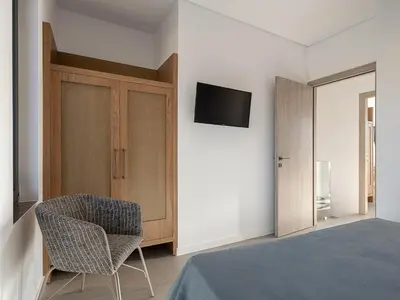 a bedroom with a bed and a chair and a tv at JnV Luxury Villas in Chania Town