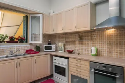a kitchen with wooden cabinets and a sink and a microwave at Dominic Chania 3 Room Apartment in Chania Town